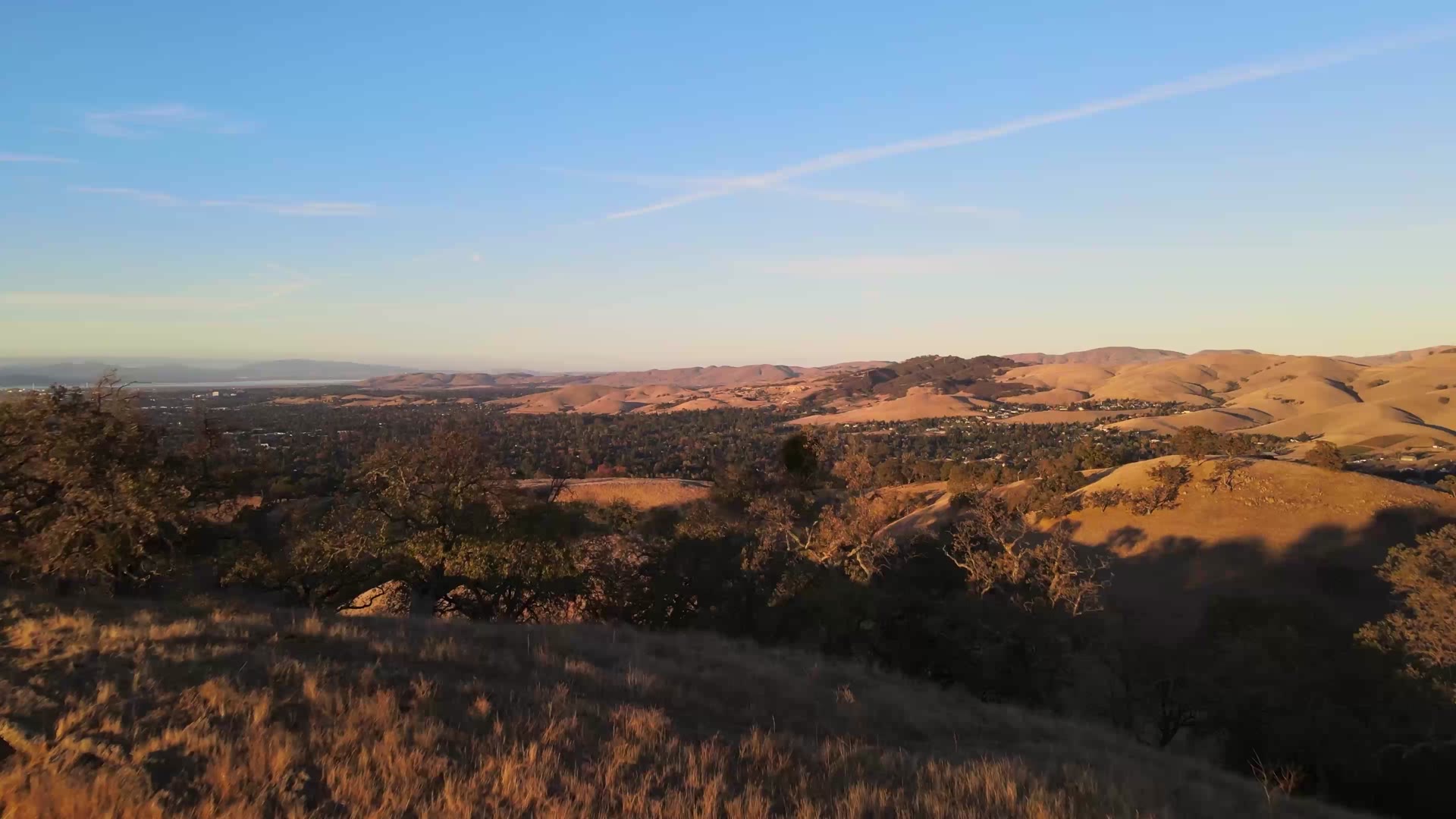 Aerial view of golden South Bay foothills and valley neighborhoods at sunset, illustrative